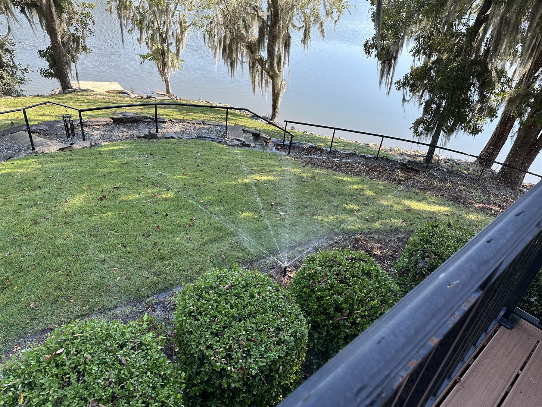 Finished lawn with active irrigation coverage at a lakeside property